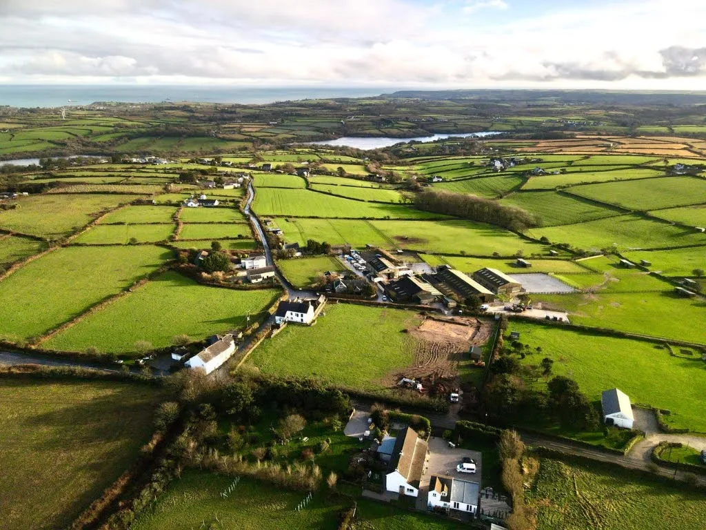 Aerial view from above Trewena looking south, the small fields of the parish in the foreground, Argal Lake mid-frame, Falmouth Bay on the horizon.