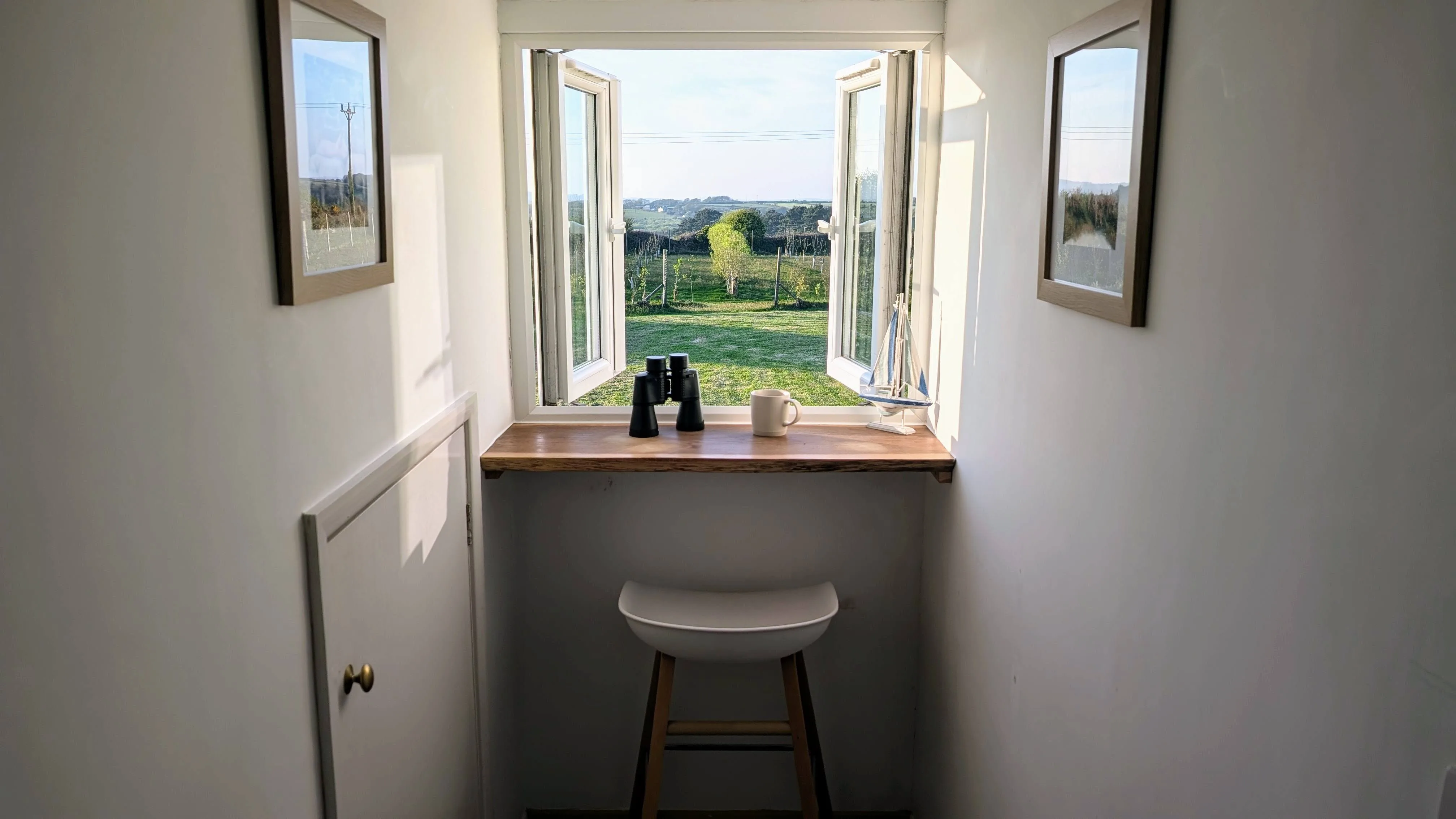 The Pigsty's upstairs reading nook by the kitchen window, with binoculars and a coffee mug on the sill.