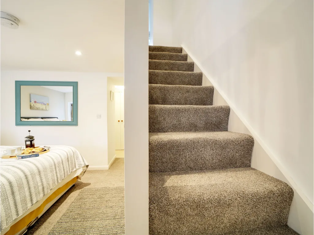 The steep staircase between The Pigsty's two floors, with the downstairs bedroom doorway on the left.