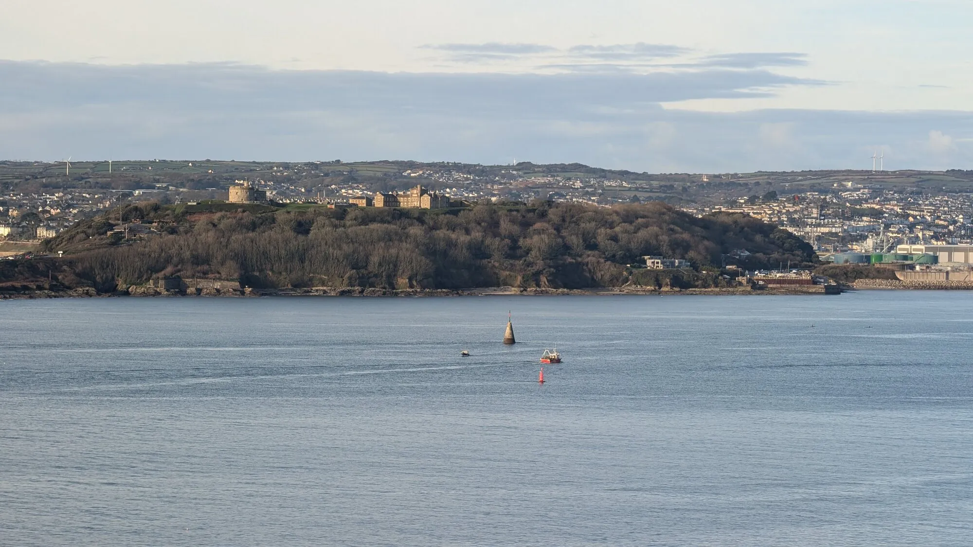 A view across Falmouth Bay to Pendennis Castle on its wooded headland, with the town and harbour beyond, captured on a calm winter morning.