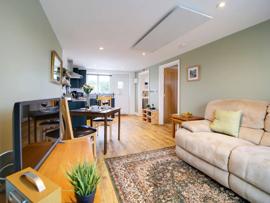 Tractor Shed living area. Open plan with sofa, wood floor, dark green kitchen visible.