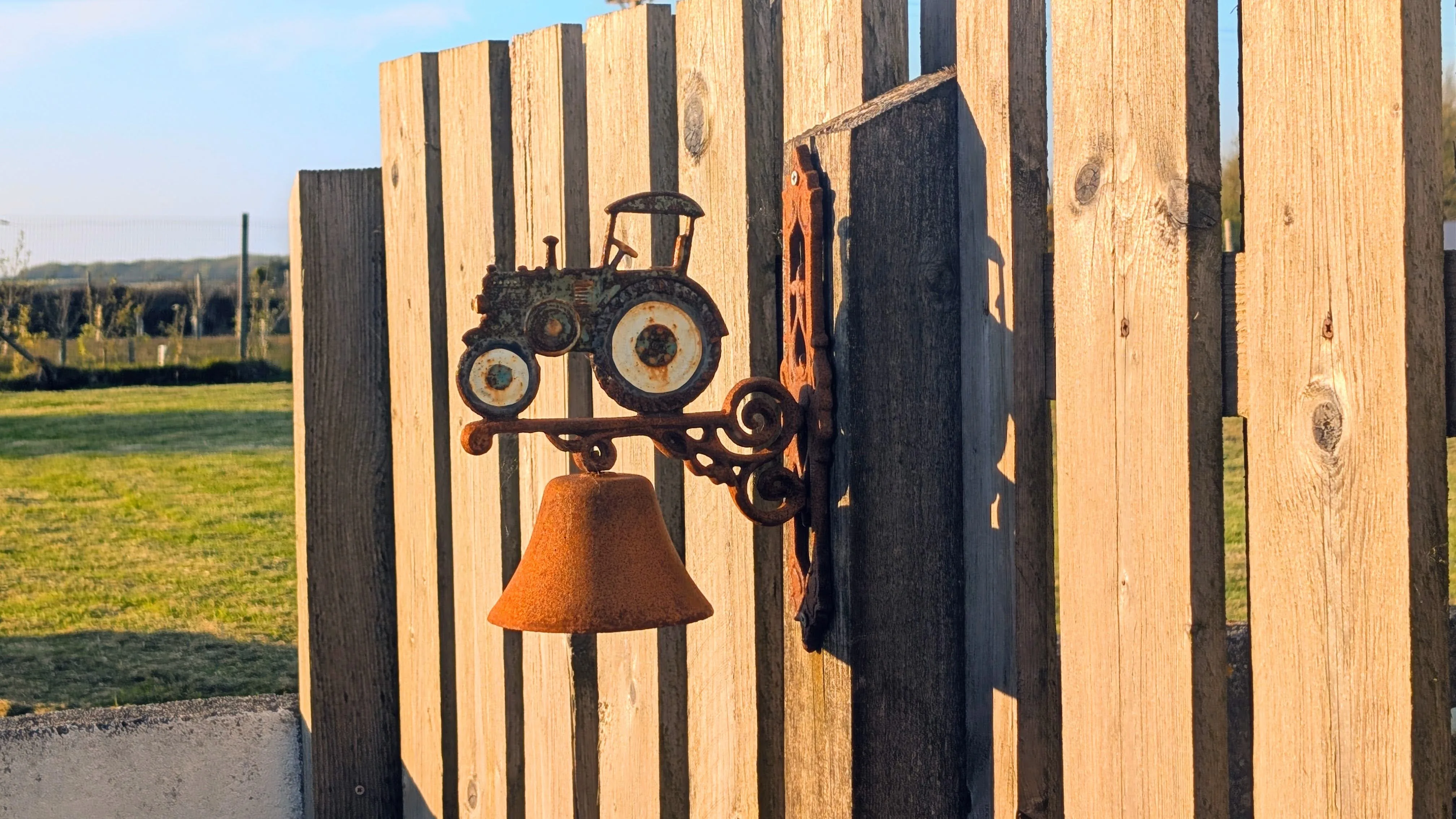 Cast-iron tractor bell on the picket fence at the Tractor Shed entrance.