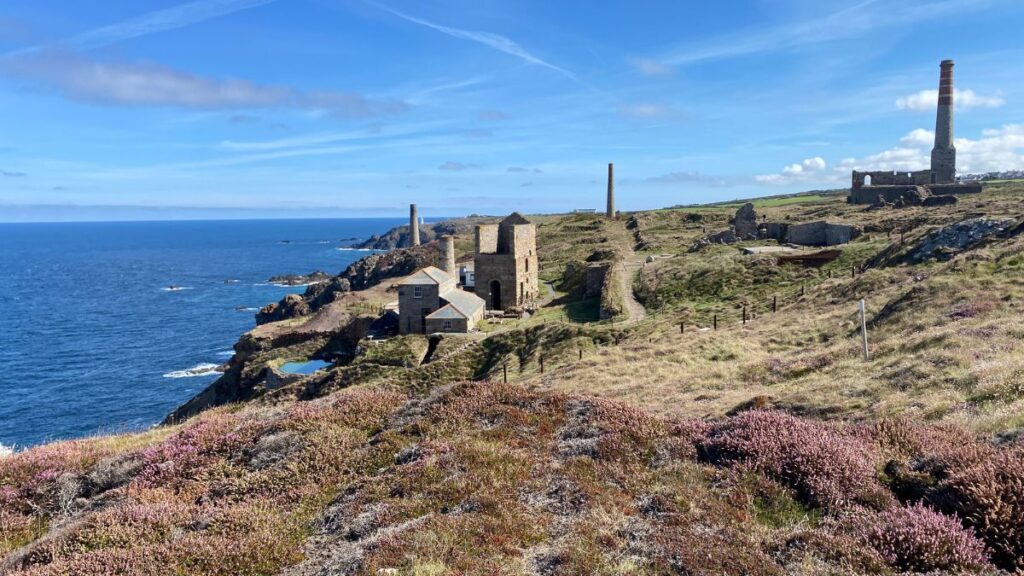 Geevor Tin Mine on Cornwall's West Penwith coast, with its historic engine house, headgear and stone buildings against the rugged moorland landscape.