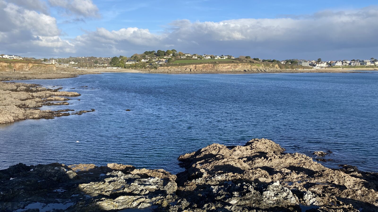 The view from Stack Point looking back across the bay to Gyllyngvase and Swanpool, with Falmouth's seafront and Pendennis headland in the distance.