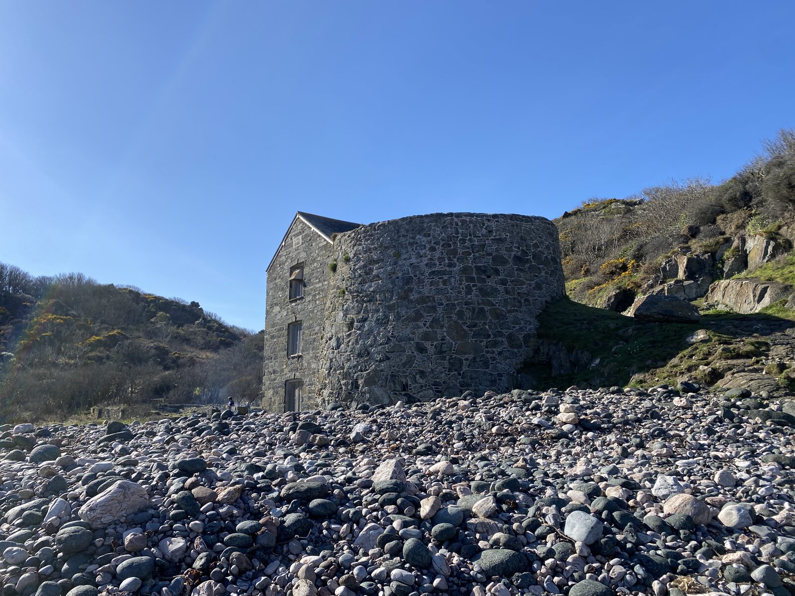 The ruins of the 19th-century serpentine works at Carleon Cove near Poltesco, with stone walls and the cove itself behind.