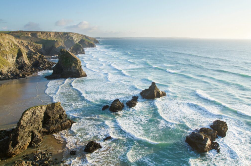 Large storm waves rolling into the bay at Bedruthan Steps on the north Cornwall coast, viewed from the high clifftop with the giant rock stacks in the foreground.