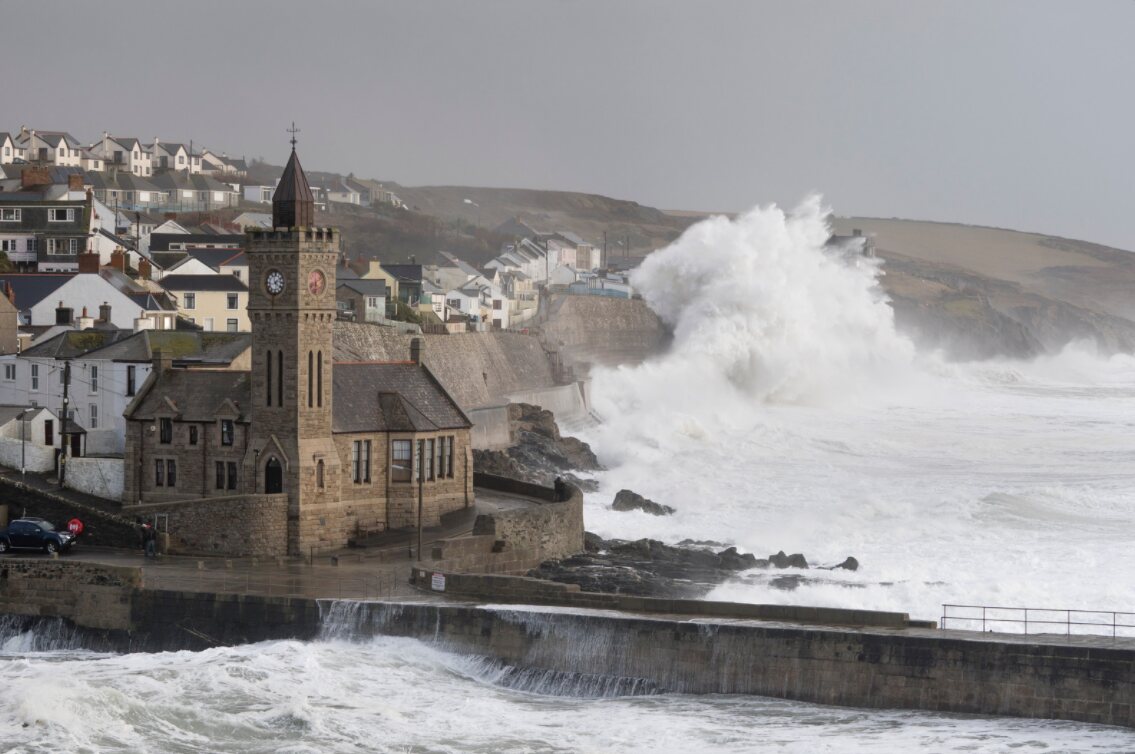 Huge storm waves crashing into the sea wall and the clock-tower Institute building at Porthleven harbour in Cornwall.