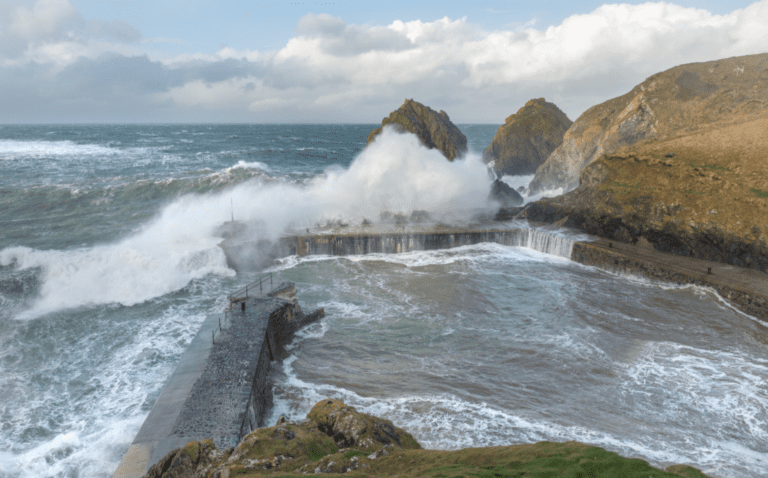 Huge storm waves crash over the small harbour wall at Mullion cove in cornwall